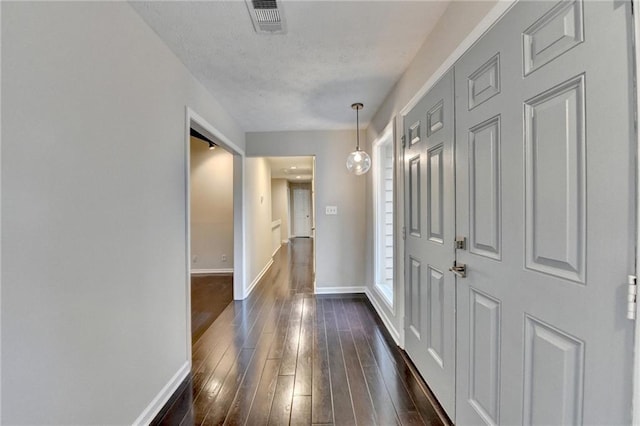 hall with dark wood-type flooring and a textured ceiling