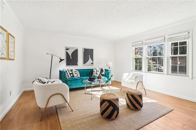 living room featuring ornamental molding, light hardwood / wood-style floors, and a textured ceiling