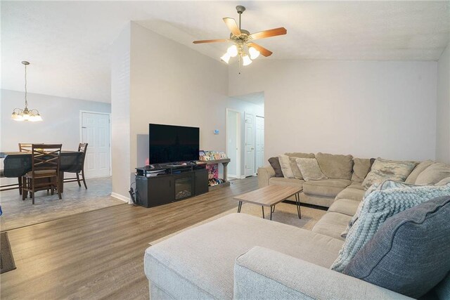 living room featuring hardwood / wood-style flooring, lofted ceiling, and ceiling fan with notable chandelier