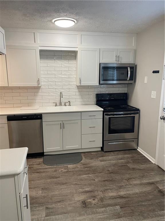 kitchen featuring appliances with stainless steel finishes, tasteful backsplash, dark hardwood / wood-style floors, and white cabinets