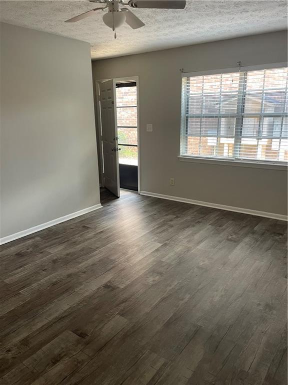 unfurnished room with ceiling fan, a textured ceiling, and dark hardwood / wood-style flooring