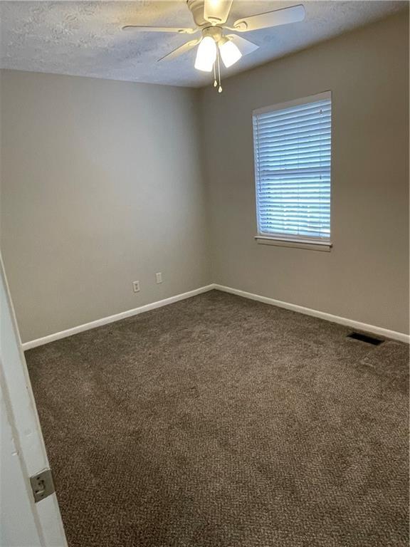 carpeted empty room featuring a textured ceiling and ceiling fan