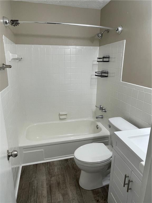 full bathroom featuring toilet, vanity, tiled shower / bath, and wood-type flooring