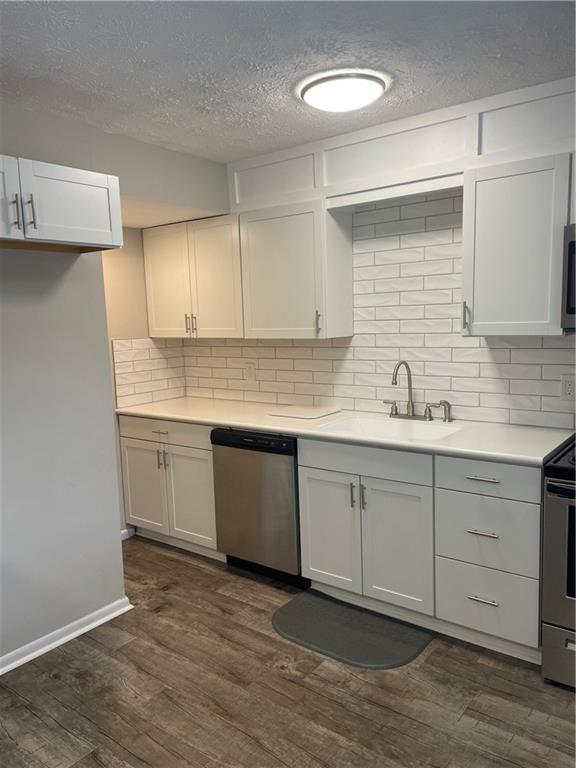 kitchen with dark hardwood / wood-style flooring, tasteful backsplash, and appliances with stainless steel finishes