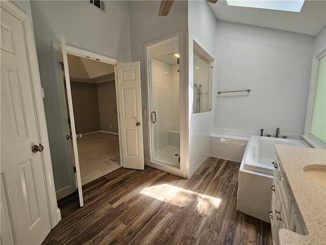 bathroom featuring a bath, a stall shower, visible vents, wood finished floors, and vanity