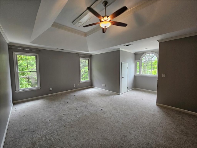 carpeted empty room with ornamental molding, a ceiling fan, a tray ceiling, and visible vents