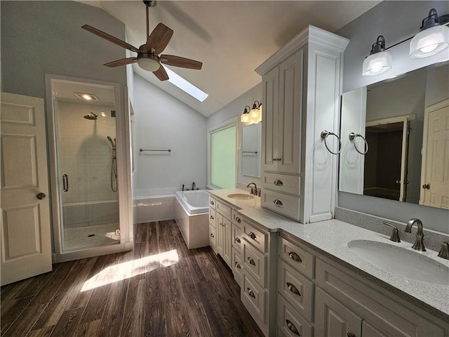 full bathroom with a stall shower, a sink, ceiling fan, and vaulted ceiling with skylight