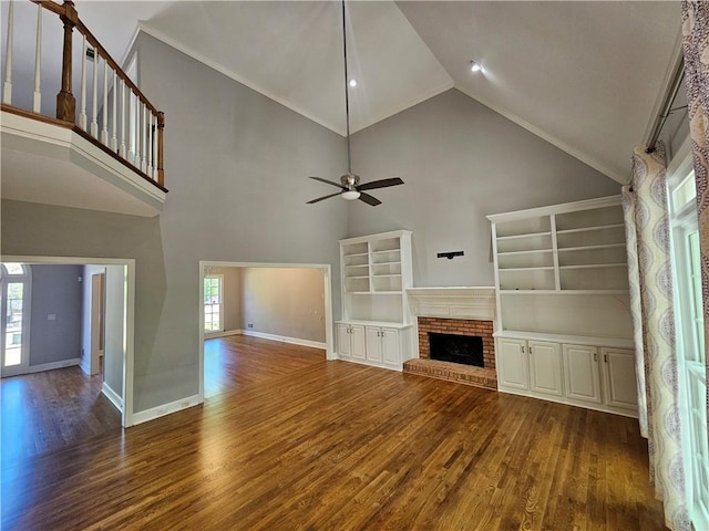 unfurnished living room featuring ceiling fan, a wealth of natural light, a brick fireplace, and wood finished floors