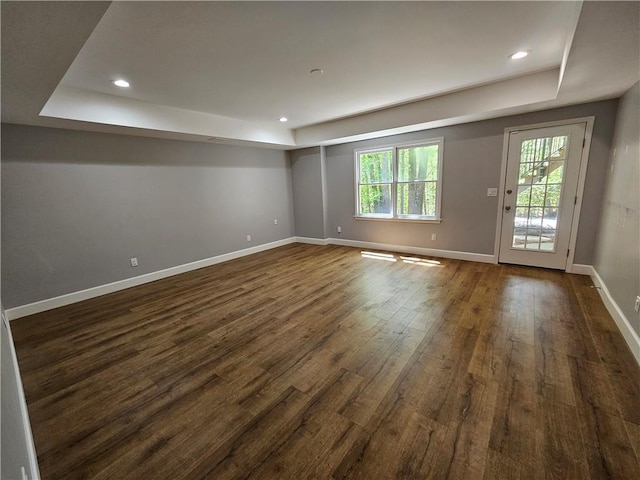 spare room with baseboards, dark wood-style flooring, a tray ceiling, and recessed lighting