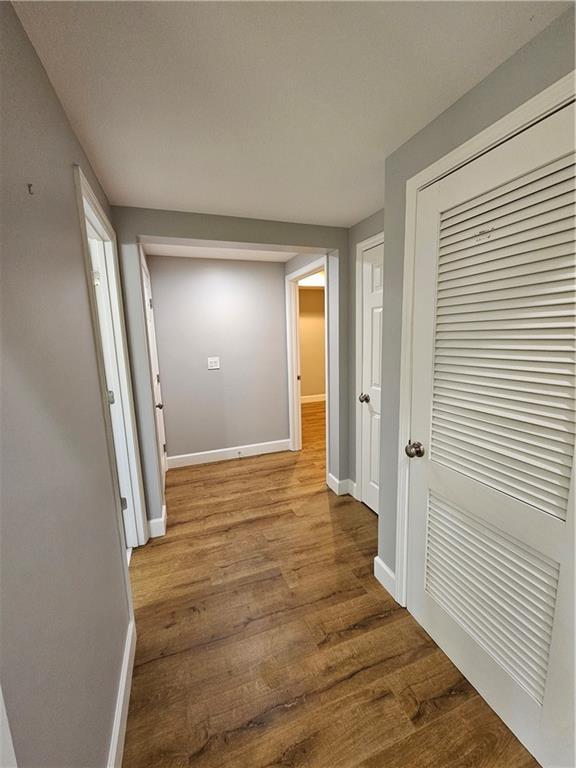 hallway with baseboards and wood finished floors