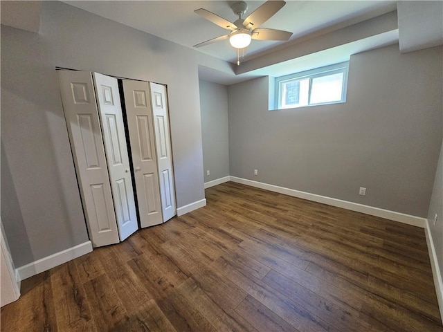 unfurnished bedroom with baseboards, a ceiling fan, wood finished floors, and a closet