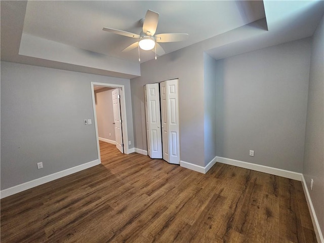 unfurnished bedroom featuring wood finished floors, a closet, and baseboards