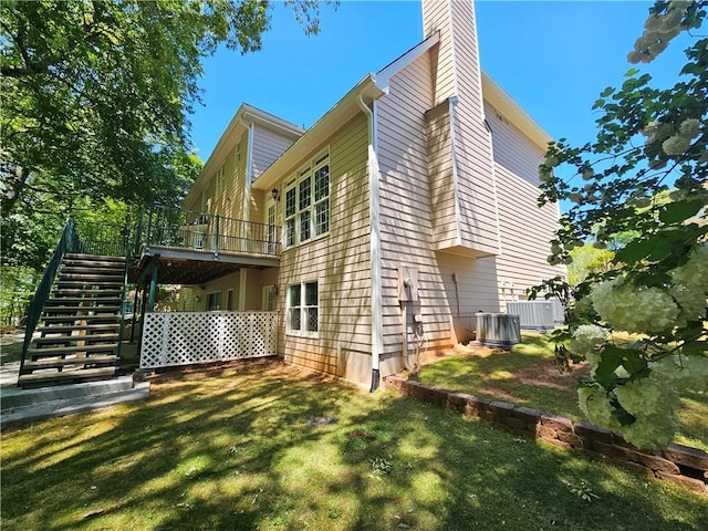 back of property with central air condition unit, a chimney, stairs, a deck, and a yard