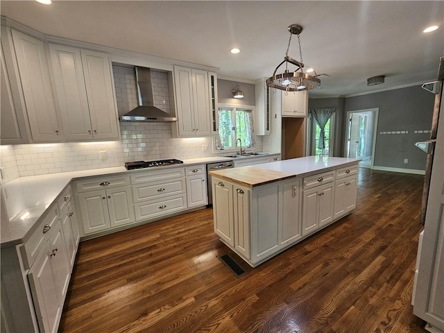 kitchen with wall chimney range hood, stainless steel dishwasher, tasteful backsplash, gas stovetop, and a kitchen island
