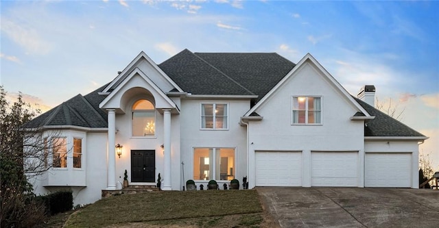 view of front of property featuring a garage, concrete driveway, roof with shingles, stucco siding, and a chimney