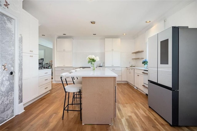 kitchen featuring a breakfast bar area, light wood-type flooring, freestanding refrigerator, and a center island