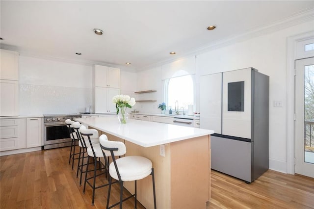 kitchen with electric range, a breakfast bar, a kitchen island, light wood-style floors, and white cabinets