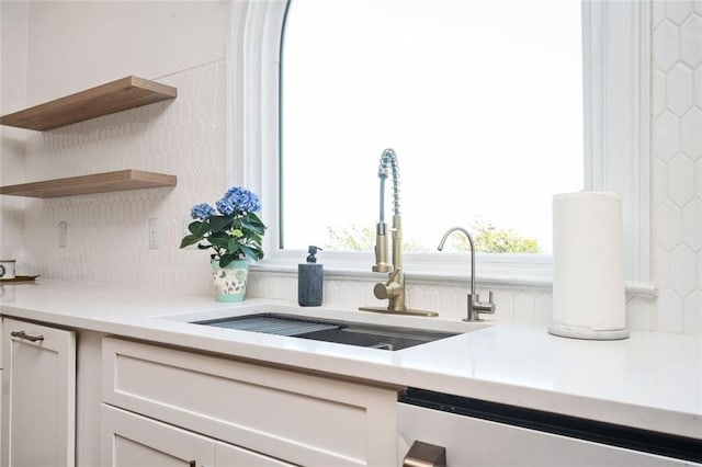 interior details with a sink, dishwashing machine, open shelves, and light countertops