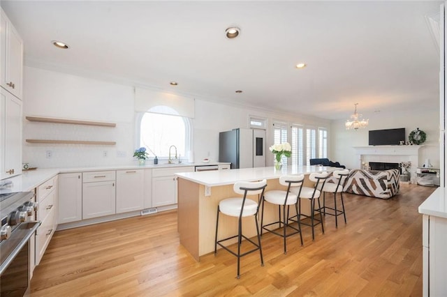 kitchen with a kitchen island, high end range, freestanding refrigerator, a sink, and a wealth of natural light