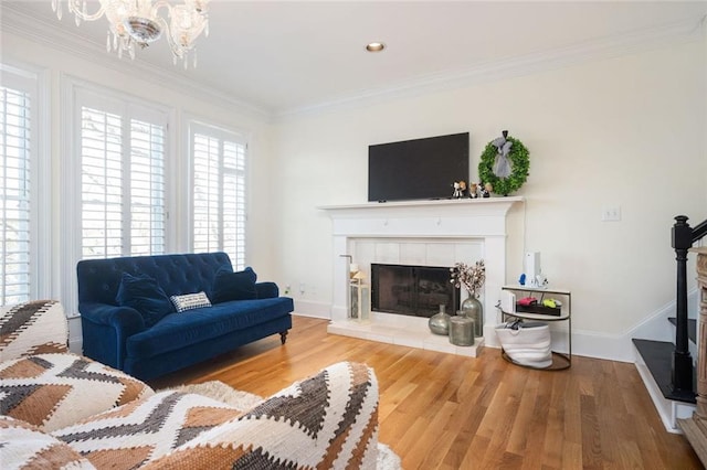 living area featuring ornamental molding, a tiled fireplace, wood finished floors, and baseboards