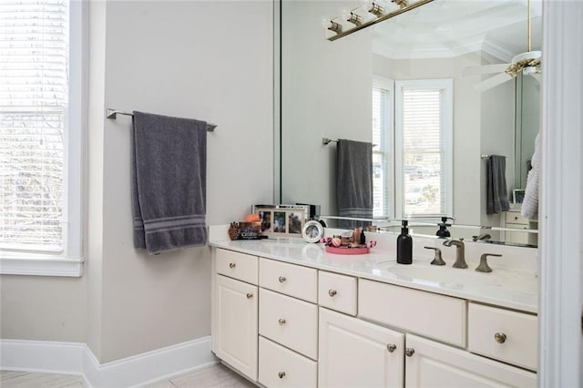 bathroom featuring ceiling fan, baseboards, crown molding, and vanity