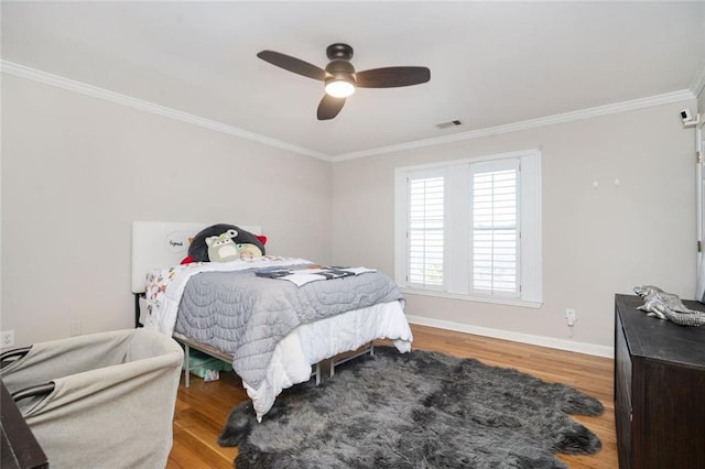 bedroom featuring ornamental molding, wood finished floors, visible vents, and baseboards