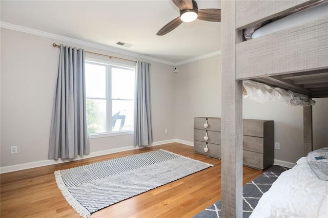 bedroom with baseboards, visible vents, ceiling fan, ornamental molding, and wood finished floors