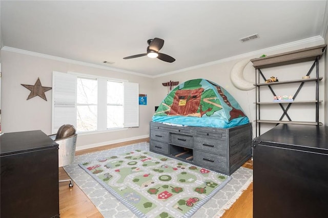 bedroom featuring visible vents, crown molding, baseboards, and wood finished floors