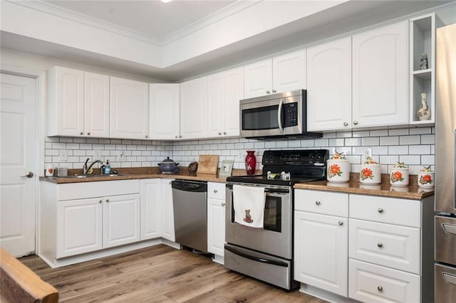 kitchen with light wood-style flooring, a sink, white cabinetry, ornamental molding, and appliances with stainless steel finishes