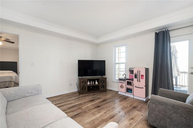 living room with baseboards, light wood finished floors, a ceiling fan, and crown molding