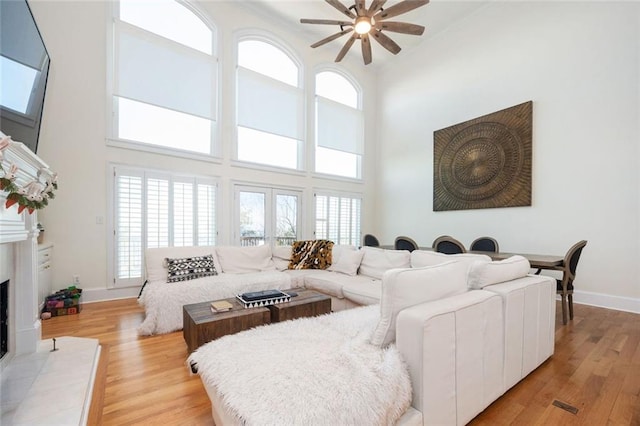 living room with baseboards, a healthy amount of sunlight, a tiled fireplace, and light wood-style floors