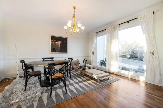 dining area with a chandelier, crown molding, and wood finished floors