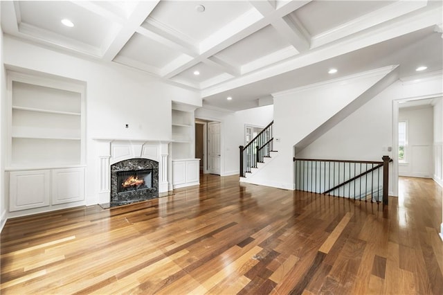 unfurnished living room with wood finished floors, built in features, beam ceiling, recessed lighting, and a premium fireplace