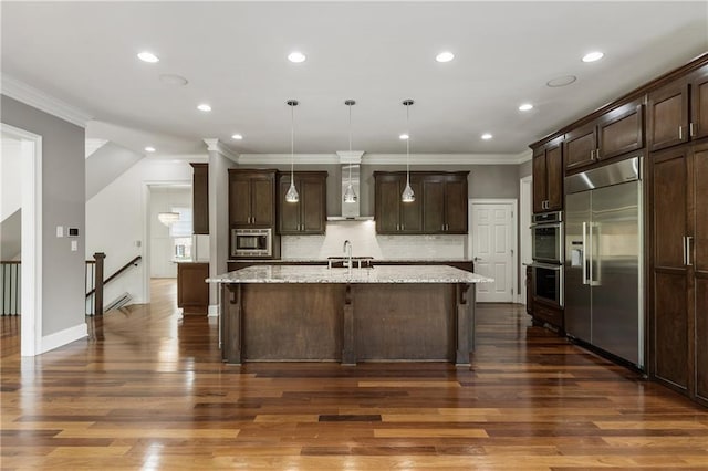kitchen with built in appliances, wall chimney exhaust hood, ornamental molding, dark brown cabinetry, and backsplash