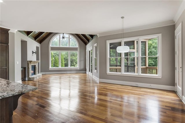 unfurnished living room with baseboards, wood finished floors, and a stone fireplace