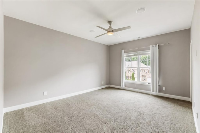 carpeted empty room featuring a ceiling fan and baseboards