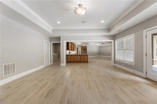 unfurnished living room featuring light wood-type flooring, baseboards, crown molding, a raised ceiling, and ceiling fan