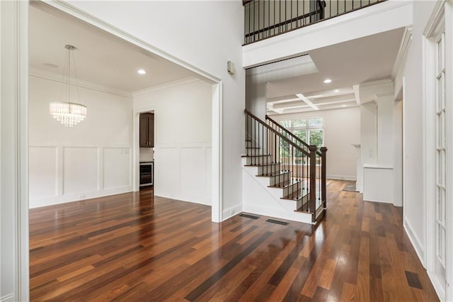 entrance foyer with a chandelier, wood finished floors, stairs, crown molding, and recessed lighting