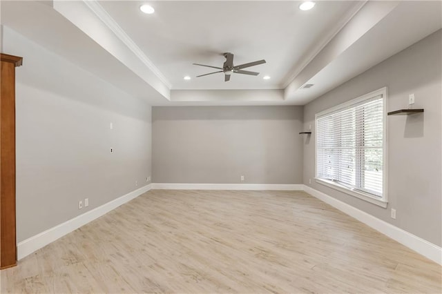 unfurnished room with a ceiling fan, a raised ceiling, ornamental molding, light wood-style flooring, and baseboards
