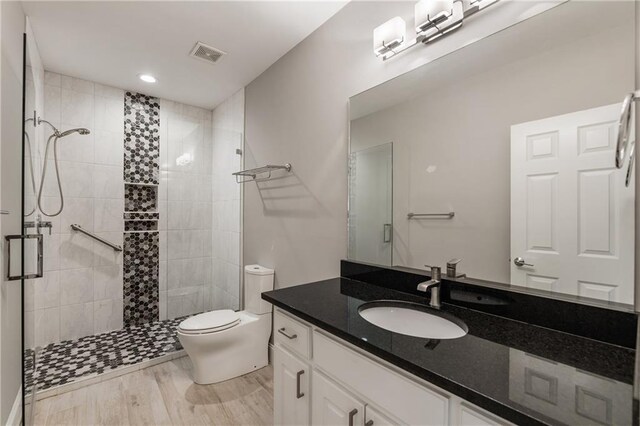 bathroom with a shower stall, toilet, vanity, and recessed lighting