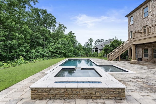 view of swimming pool with a lawn, stairway, a patio, and a pool with connected hot tub