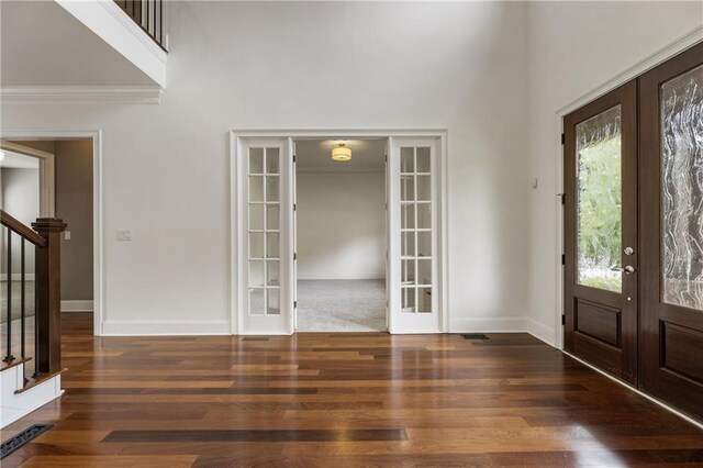 entryway featuring french doors, stairs, a high ceiling, wood finished floors, and ornamental molding