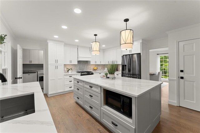 4433 Windsor Oaks Cir, Marietta, GA 30066 - kitchen with stainless steel fridge, black microwave, custom range hood, crown molding, and tasteful backsplash