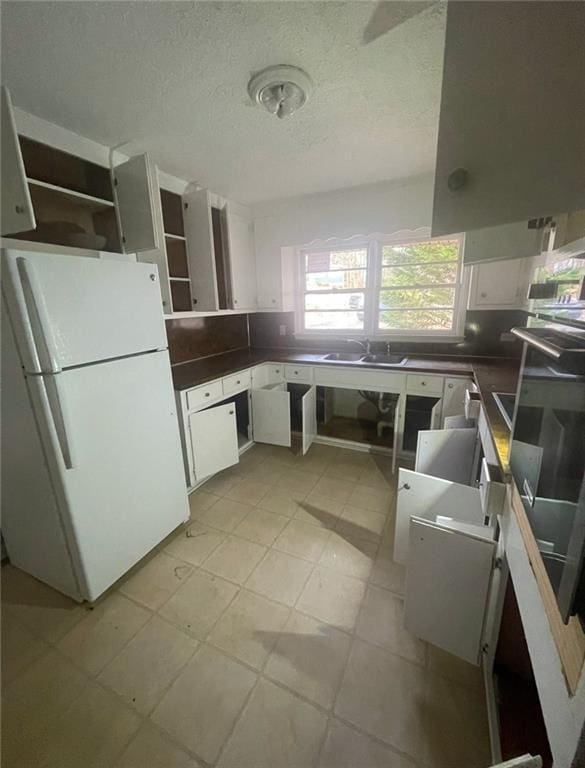 kitchen featuring white cabinetry, sink, white fridge, and a textured ceiling