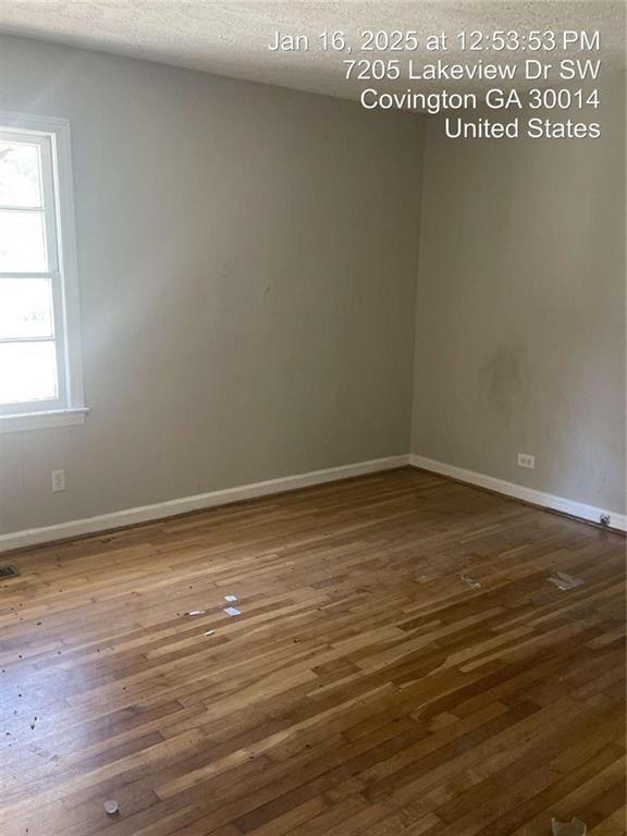 empty room with dark hardwood / wood-style floors and a textured ceiling