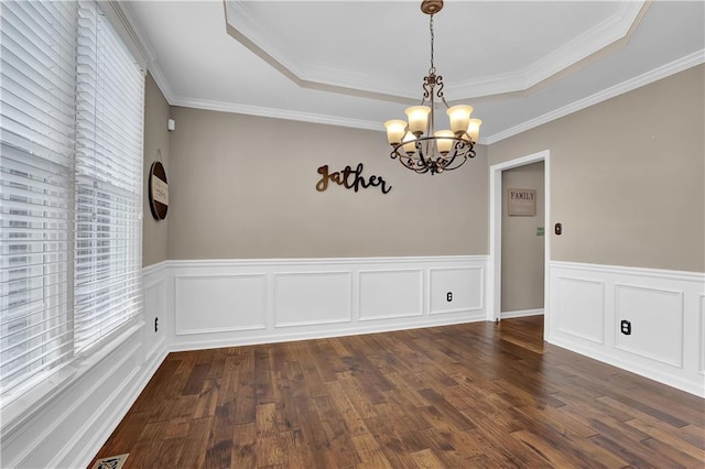 empty room with dark wood-type flooring, ornamental molding, a tray ceiling, and a chandelier