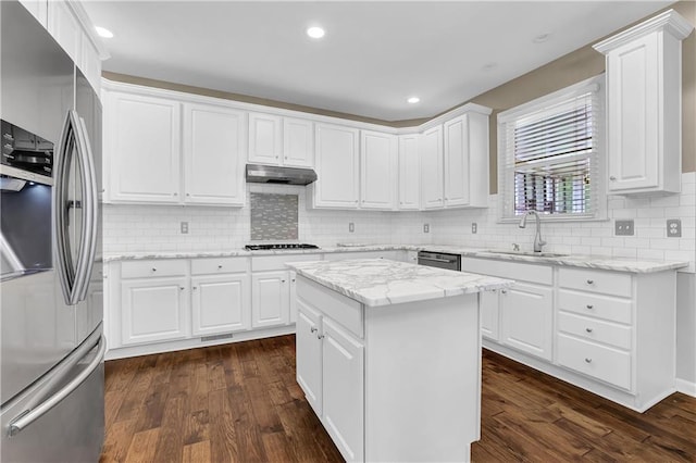 kitchen featuring dark wood-type flooring, sink, stainless steel appliances, white cabinets, and a center island