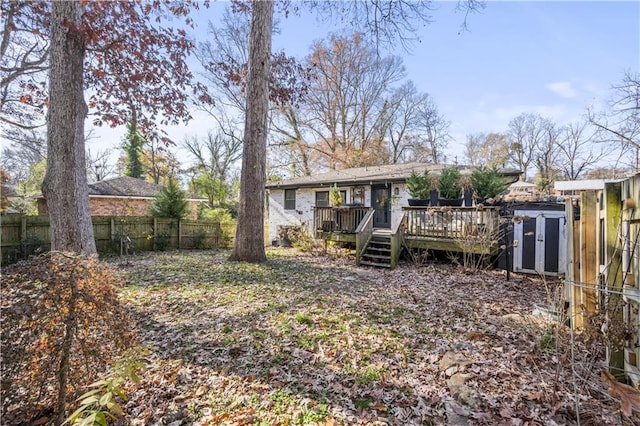 rear view of house with a wooden deck and a storage unit