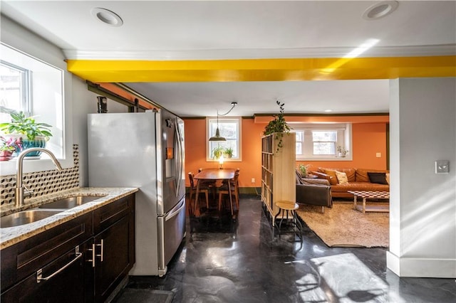 kitchen with stainless steel fridge with ice dispenser, backsplash, decorative light fixtures, and sink