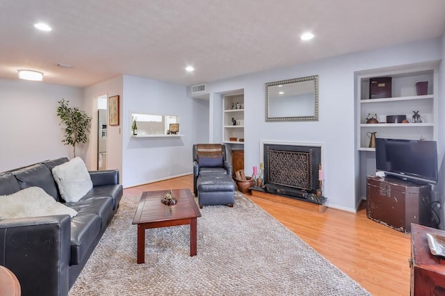 1418 Summit N Dr NE Unit 1418, Atlanta, GA 30324 - living room with a fireplace with raised hearth, built in features, recessed lighting, light wood-type flooring, and visible vents